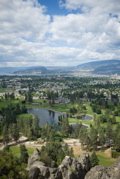 Image: city of Kelowna with golf course in foreground, lake & mountain in background.